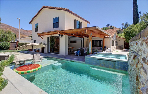 a house with a pool and floatie with umbrella